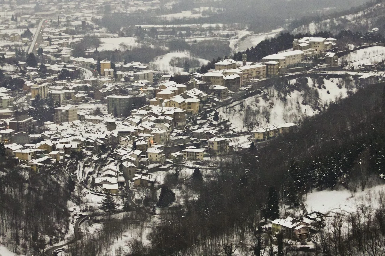 Veduta invernale di Lanzo Torinese innevata, con il centro abitato adagiato sul fianco della valle
